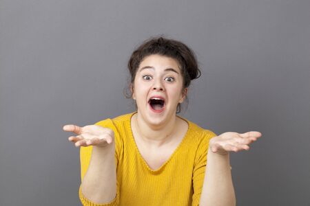 funny beautiful overweight girl laughing with euphoric smile and playful hands in foreground wearing yellow sweaterの写真素材