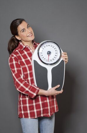 healthy 30s woman holding a weight scale, symbol of healthcareの写真素材