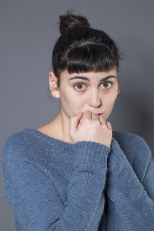 surprise and disappointment concept - portrait of a crying 20s brunette woman with confused eyes and hands together,studio shotの写真素材