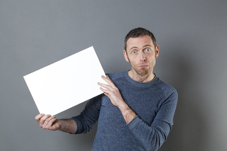 stunned 40s man looking surprised in holding a stressful news on a blank white boardの写真素材