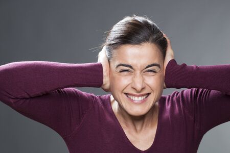 raging young woman covering closed ears, annoyed by loud noise, ignoring someone, not wanting to hear their side of story or having painful headacheの写真素材