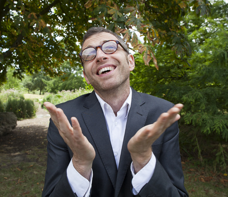 mad scientist outdoor concept - excited businessman smiling,saying thank you in looking up to the sky in green background for corporate management,natural summer daylightの写真素材