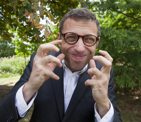 mad scientist outdoor concept - passionate tensed businessman discussing with crazy hand gesture in green background for corporate leadership,natural summer daylightの写真素材