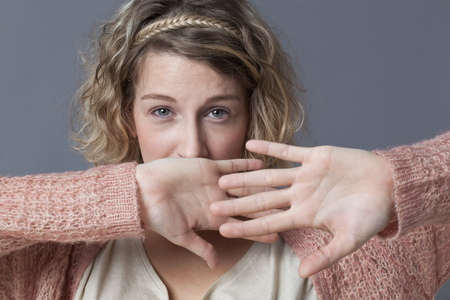 surprise and fear concept - afraid 20s woman with short curly hair protecting herself with her...
