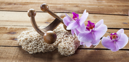 concept of massage and washing-up with loofah glove, wooden accessory and orchid flowers for wellbeingの写真素材