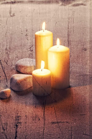 zen still life for spa and massage with big candles and white stones for meditation with textured and contrast effects for retro ambianceの写真素材