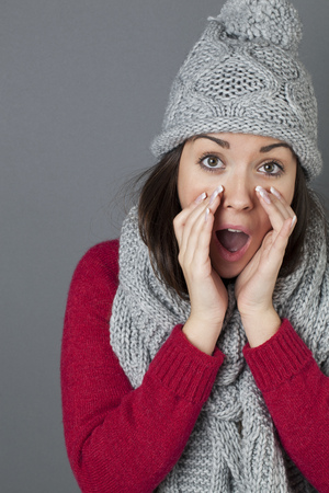 vocal concept - portrait of happy 20s woman with winter grey winter hat and scarf shouting with hands around mouth,studio shotの写真素材