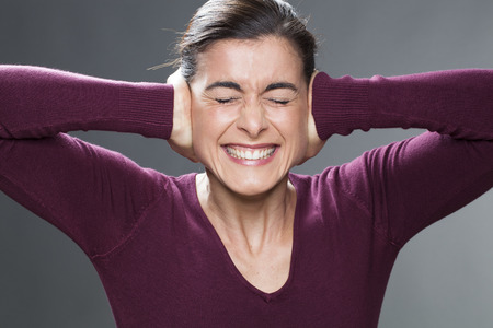 annoyed young woman covering closed ears, annoyed by loud noise, ignoring someone, not wanting to hear their side of story or having painful headacheの写真素材