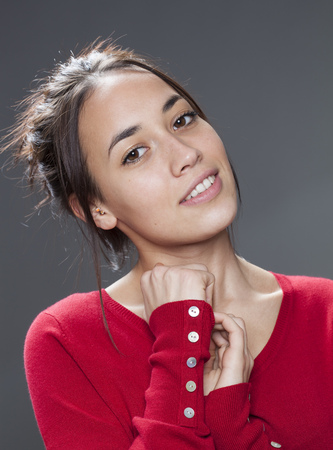 seduction concept - portrait of beautiful mixed-race girl smiling protecting herself with hands to her chest for self-assurance,studio shotの写真素材