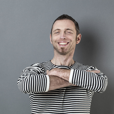 satisfaction and smile concept - thrilled middle age man with both arms folded in front of him expressing happiness and wellbeingの写真素材