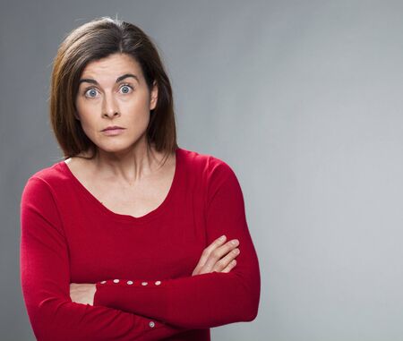 surprise and disappointment concept - portrait of a brunette businesswoman with arms folded questioning people,studio shot,copy spaceの写真素材