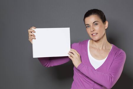 beautiful young woman holding a claim on blank communication boardの写真素材