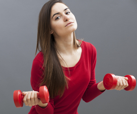 slim young woman wearing business clothes holding heavy dumbbells for workout at the officeの写真素材