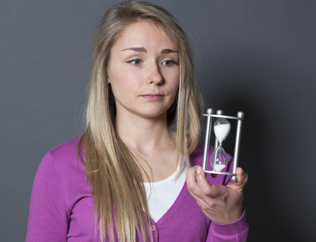 calm young blond woman holding hourglass for concept of time managementの写真素材