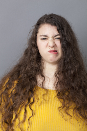 unhappiness and disappointment concept - young overweight woman with long brown hair expressing concern with a funny face for fun complain,studio shotの写真素材