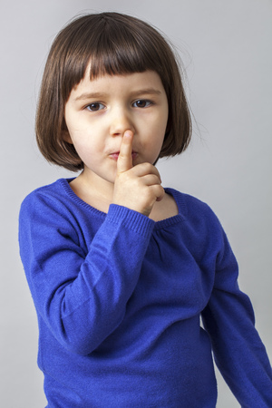 young preschool girl wanting to keep a secret with her finger on lipsの写真素材