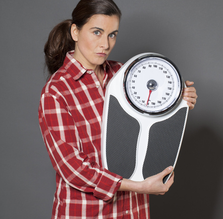 casual 30s woman skeptical about her scales for weight lossの写真素材