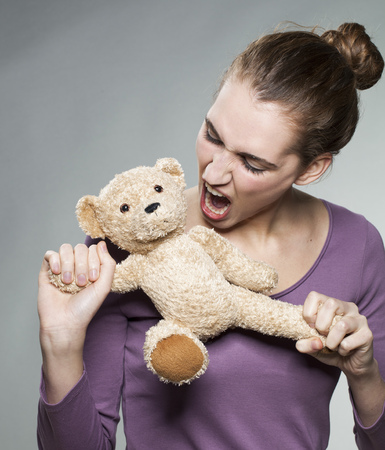 furious young woman torturing teddy bear for growing up or teenager nervous breakdownの写真素材