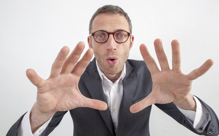 expressive corporate man concept - weird middle age businessman playing with his hands,hypnotizing or manipulating,wide angle on white backgroundの写真素材