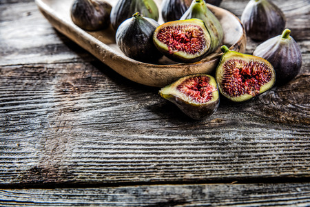 fruit still-life - group of organic figs,whole and cut,on wooden tray set on wood background for...