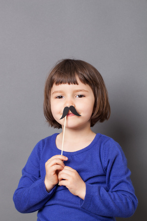 kid moustache concept - happy 4-year old Charlie Chaplin look alike dressing up with a fake mustache studio shotの写真素材