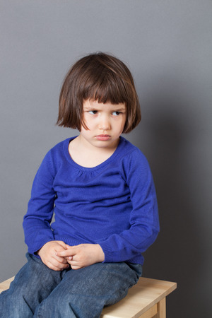 kid attitude concept - thinking 4-year old child sulking on a stool for discipline or calming down in the corner for bad behavior,studio shotの写真素材