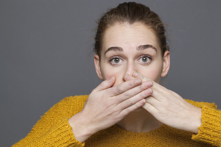negative feelings concept - dumbstruck beautiful 20s girl covering her mouth for regret or...