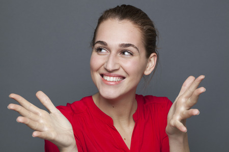 winning behavior concept - gorgeous 20s girl laughing and gesturing for wellbeing and happiness,studio shot on gray backgroundの写真素材