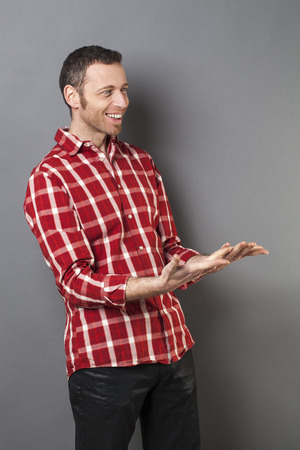 hand gesture concept - excited 40s man with checked shirt holding something heavy in empty hands,studio shotの写真素材