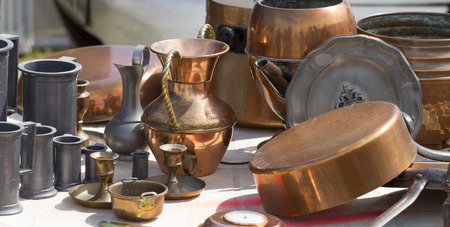 old copper carafes and pans displayed for sale at second hand shop