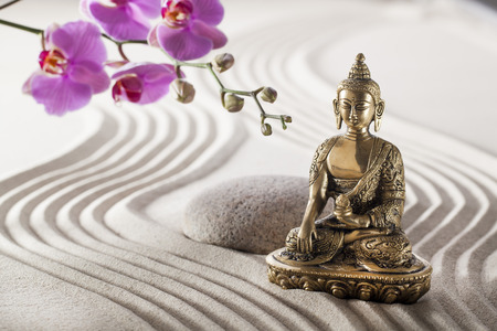 bronze Buddha in zen flower garden with smooth lines and grooves in sandの写真素材