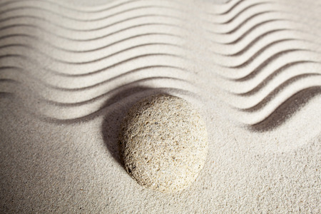 top view of sinuous path in zen sand for philosophy of life with one round pebble or stone set on the border wavesの写真素材