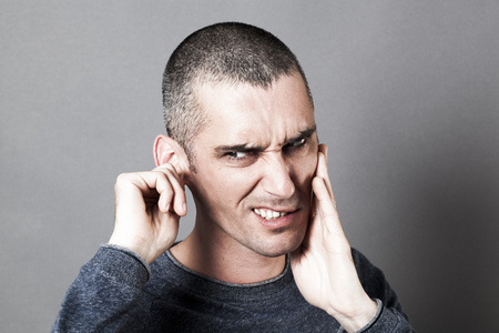 noise and hearing concept - nervous young man suffering from toothache or earache, touching his face for pain, contrast effectsの写真素材