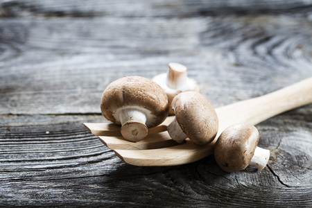 vegetable still life - Paris mushrooms on new wooden salad fork on retro wood background, studio shotの写真素材