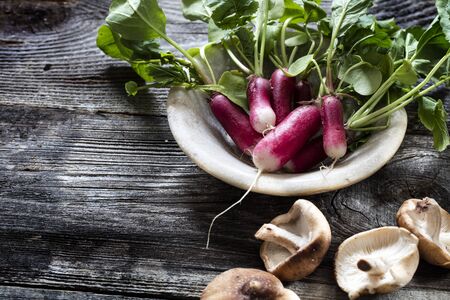 vegetable still life - freshly cut radishes and shiitake mushrooms on old wooden background for vegetarian home-made cuisine, studio shotの写真素材