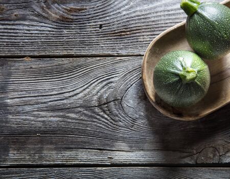 vegetable still life - green round zucchinis on authentic old wooden background for home-made diet, studio shot, top viewの写真素材