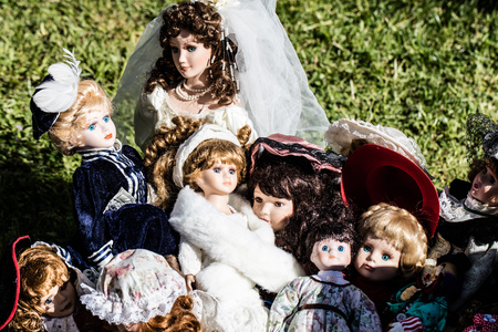 display of various vintage and old ceramic dolls for collectors and collection at garage sale of flea market, outdoorsの写真素材