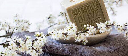 organic detox still-life - green Marseille soap with olive oil over towel and fresh white spring blossom flowers for body care beauty treatmentの写真素材
