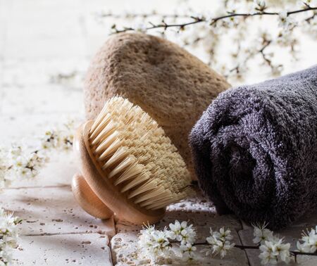 zen detox still-life - closeup of body brush and towel over stone, fresh white spring flowers and mineral limestone background for body care beauty treatmentの写真素材