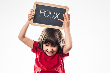 furious young child holding a school slate with 'poux' written in French on it, fighting against head lice, white background studioの写真素材