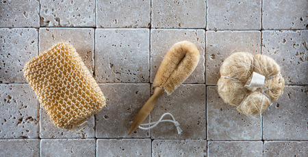 dry brushing with a set of natural loofah sponges and brush for pampering massage over simple clean limestone background, flat layの写真素材