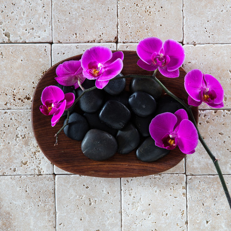 wellness spa concept with black massage pebbles and pink orchids over wood and pure limestone background for zen wallpaper, flat layの写真素材