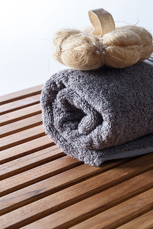 closeup of loofah mitt for purifying body care on rolled up grey cotton towel for pure exfoliation and hygiene, copy spaceの写真素材