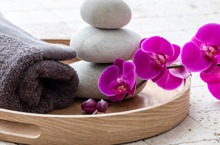 mindfulness and balance concept for natural body massage after bath over feng shui stones and rolled up grey towel and wooden trayの写真素材