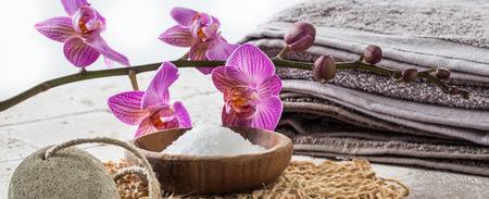 washing up concept with bath salt, pumice stone, cotton towel, loofah mitt and pink flowers for natural softening bathの写真素材