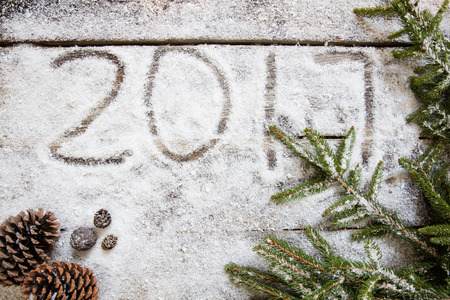 Announcing 2017 on winter snowy wallpaper with frozen fir cones and twigs for white winter, New Year background and holiday announcement, top viewの写真素材