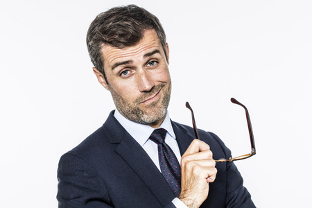 smiling bearded middle aged businessman with a tie holding his eyeglasses for corporate vision, copy space, white background studioの写真素材