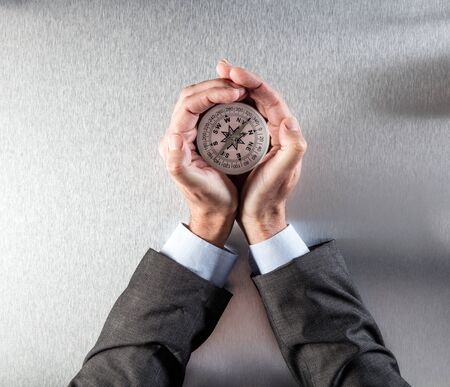 businessman hands protecting a compass in his palms, searching for and leading the company...
