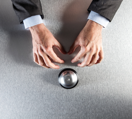 complaining businessman hands waiting next to an office bell for nervous customer assistance and workplace management, copy space, flat layの写真素材