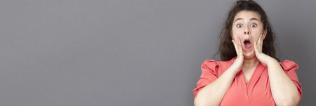 surprise and success concept - extrovert big woman shouting for surprise and happiness with vintage pink dress, long grey bannerの写真素材